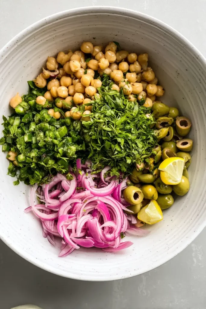 Chickpeas, herbs, olives, and red onion prepped for Marinated Zaatar Bean Salad