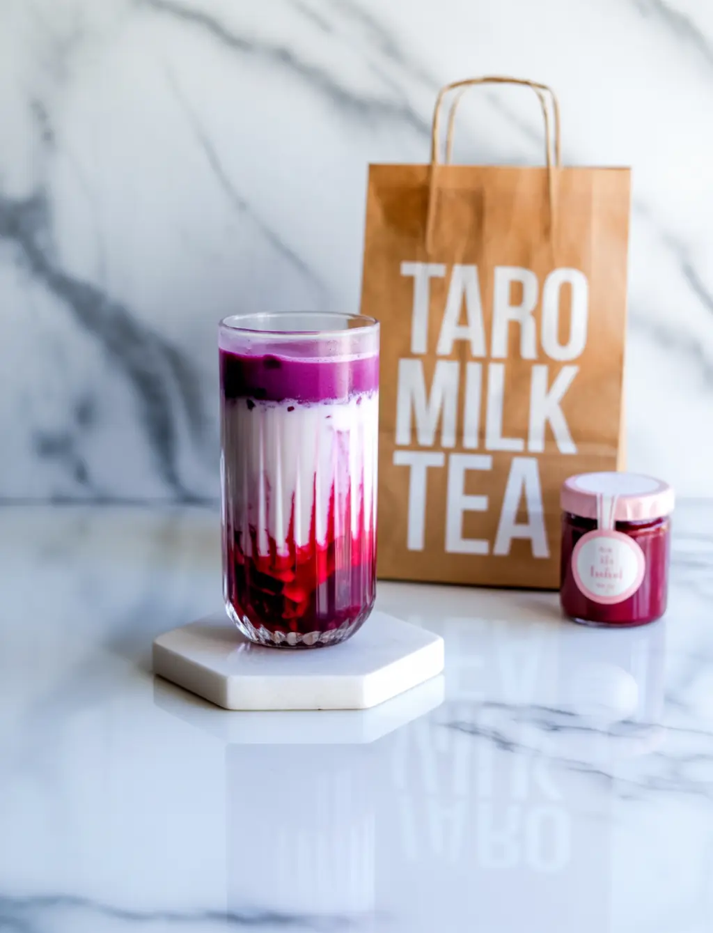 Pastel taro milk tea in clear tall glass on marble